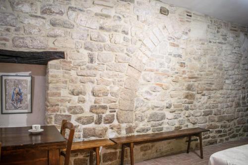 a room with a stone wall with a wooden table at Monolocale centro storico in Gubbio