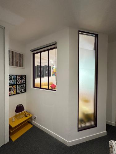 a room with a white wall with a window and a table at POP appART Appartement Artiste configuré en Galerie dArt à 200 m du centre ville avec Parking privé et securisé gratuit dans copropriété in Avignon