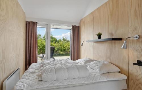 a bedroom with a large white bed with a window at Holiday Home Kronvildtvej Iv in Brovst
