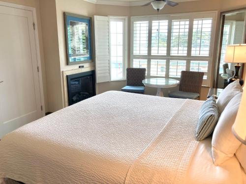 a bedroom with a bed and a table and windows at Sand Pebbles Inn in Cambria