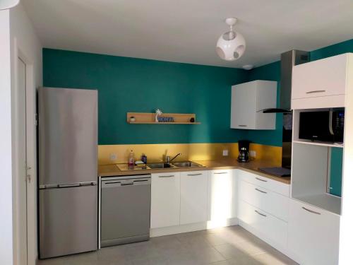 eine Küche mit weißen Schränken und einer grünen Wand in der Unterkunft CAP MONTA - Maison Neuve in Vendays-Montalivet