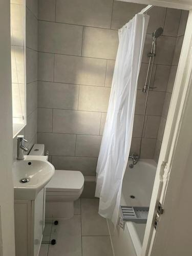 a bathroom with a toilet sink and a shower curtain at 2 bed flat with balcony, TV & Great transport in Edmonton