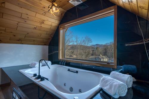 a bathroom with a tub and a large window at The Haüs Windham in Windham