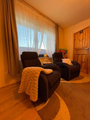 ein Wohnzimmer mit 2 Stühlen, einem Sofa und einem Fenster in der Unterkunft Przyszowa 441 in Przyszowa