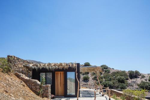una pequeña casa con techo de paja en una colina en Muar Suites en Agios Pavlos