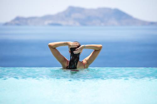 Una mujer en el agua con las manos en la cabeza en Muar Suites en Agios Pavlos