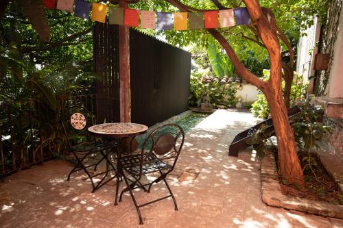a patio with a table and chairs and a tree at Alko Hotel Casa Nispero in Cali