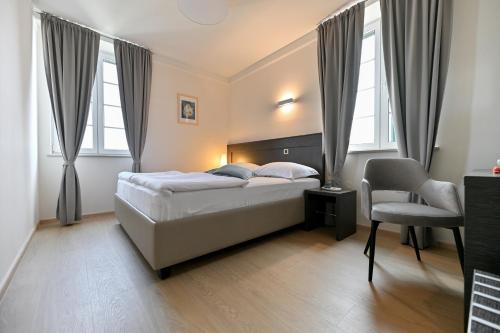- une chambre avec un lit, une chaise et des fenêtres dans l'établissement Villa Hrešć S, à Zadar