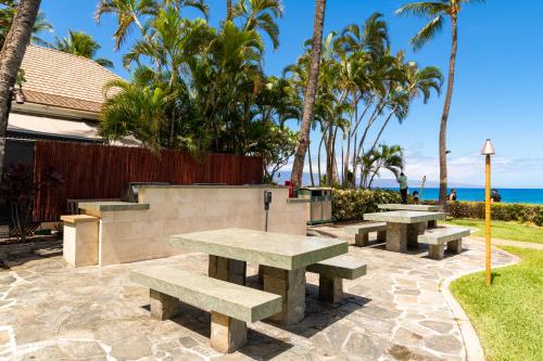 a group of picnic tables with the beach in the background at The Whaler Resort in Lahaina