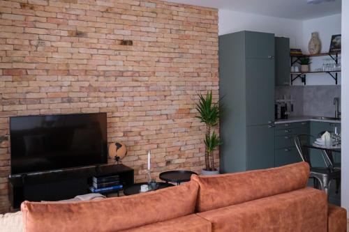 un soggiorno con divano e muro di mattoni di Cityscape Apartment ~ AC/Indoor parking/Balcony a Budapest