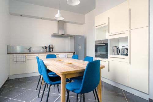 a kitchen with a wooden table and blue chairs at Coeur de ville #H3 - WIFI et NETFLIX - Lave linge - Logement partagé - Chambre privée in Cholet