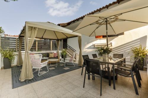 a patio with a table and chairs and umbrellas at Azure Breeze - Coastal Chic Getaway by the Sea in Psakoudia