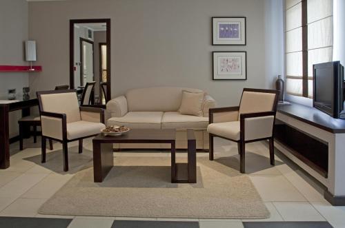 a living room with a couch and chairs and a tv at Garni Boutique Hotel Arta in Novi Sad