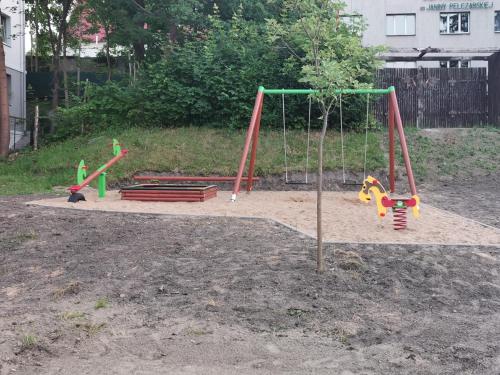 a playground with three swings in a yard at Harmony Apartment in Ostróda