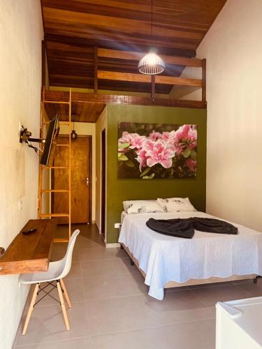a bedroom with a bed and a painting of flowers at Chales em Salesopolis - Recanto da Barra in Salesópolis