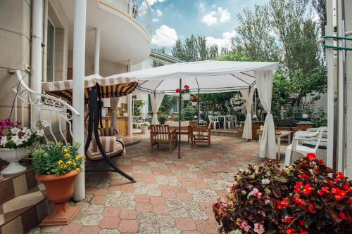 a patio with a white umbrella and tables and chairs at Vilari Odessa in Odesa