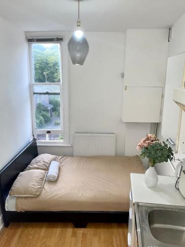Bett in einem kleinen Zimmer mit Fenster in der Unterkunft Great location studio apartment with Smart TV and workspace in London