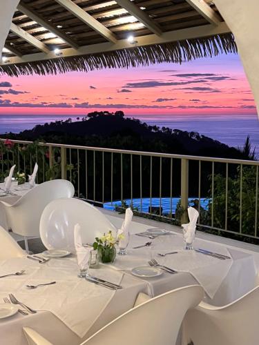 a table with white chairs and a view of the ocean at Hotel La Mariposa in Manuel Antonio