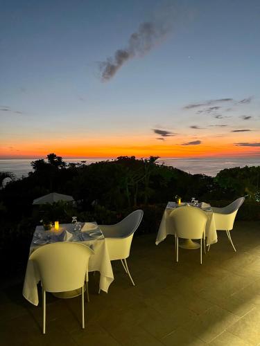 two tables and chairs with a sunset in the background at Hotel La Mariposa in Manuel Antonio