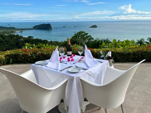 a table with white chairs and a bottle of wine at Hotel La Mariposa in Manuel Antonio