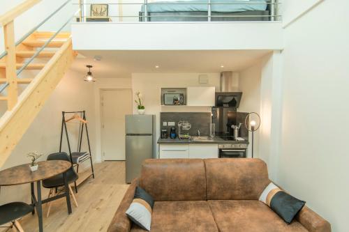 een woonkamer met een bank en een keuken bij KASA FACTORY - Au calme - TV & WIFI in Saint-Quentin