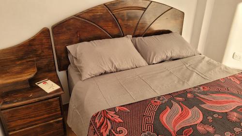 a bed with a wooden headboard next to a table at Apartment with amazing view in Huancayo