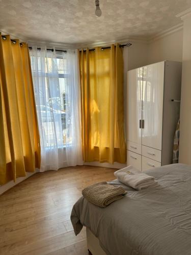 a bedroom with yellow curtains and a bed and a window at Beautiful 4 bedroom house in Enfield in Enfield Lock