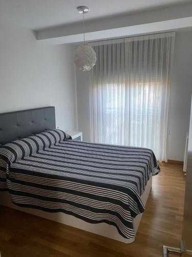 Un dormitorio con una cama con una manta a rayas. en APARTAMENTO PLAYA A XUNQUEIRA, en Moaña