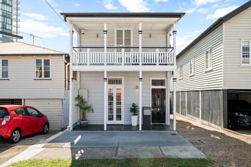 a white house with a red car parked in the driveway at Amelia Terrace - House in Brisbane City Central in Brisbane