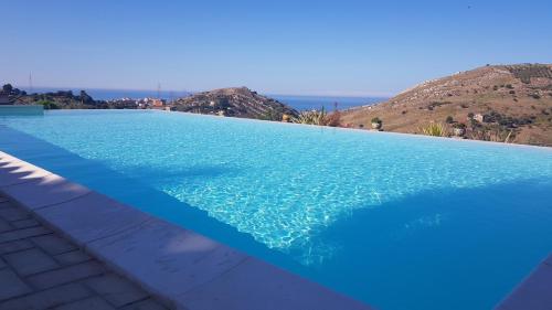 a blue swimming pool with a view of the ocean at B&B A Robba de Pupi in Agrigento