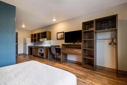 a room with a bed and a desk with a television at WoodSpring Suites Panama City Beach in Panama City Beach