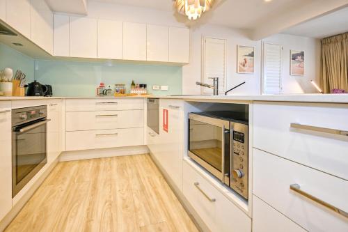 a kitchen with white cabinets and a wooden floor at Stylish 2 b/r apartment - 4 guests, garage ZC5 in Alexandra Headland