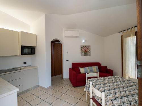 a kitchen and a living room with a red couch at Centro Servizi Marinella in Marinella