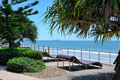 two benches sitting on a sidewalk near the beach at Stylish 2 b/r apartment - 4 guests, garage ZC5 in Alexandra Headland