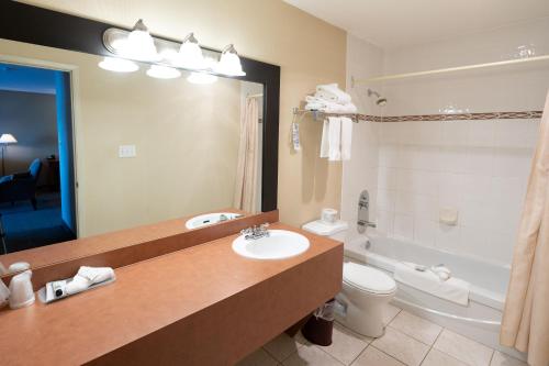 ein Badezimmer mit einem Waschbecken, einem WC und einem Spiegel in der Unterkunft Anchor Inn and Suites in Campbell River