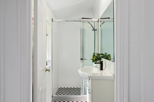 a white bathroom with a sink and a shower at Amelia Terrace - House in Brisbane City Central in Brisbane