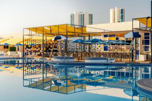 ein Pool mit Tischen und Sonnenschirmen und ein Gebäude in der Unterkunft The STRAT Hotel, Casino & Tower in Las Vegas