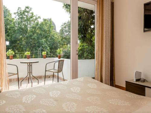 a bedroom with a bed and a balcony with a table and chairs at Amidst Monuments and Serenity in New Delhi
