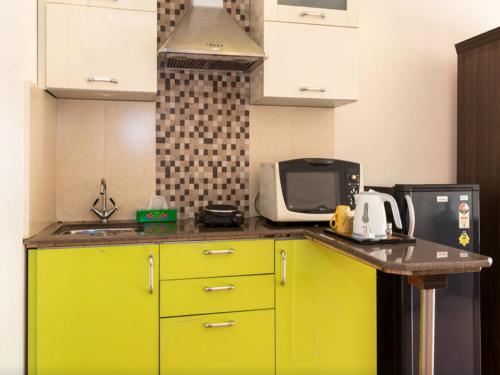a kitchen with yellow cabinets and a microwave at Amidst Monuments and Serenity in New Delhi