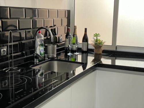 a kitchen counter with a sink and bottles of wine at Apartamento playa Fuengirola centro paseo marítimo in Fuengirola