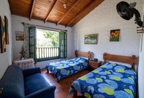 1 dormitorio con 2 camas, sofá y ventana en Jicaleja, en Palmira