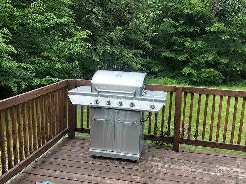 a grill sitting on a deck on a wooden fence at APPLEJAX cabin steps from a u pick orchard in Sandisfield