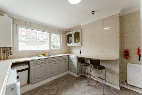 a kitchen with gray cabinets and a sink and two stools at CanningTown Double Rooms - 20 in London