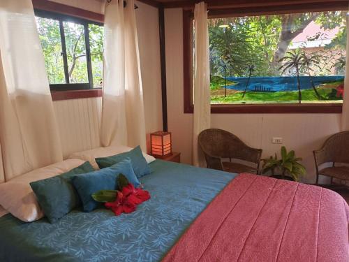Un dormitorio con una cama con una flor roja. en Cabañas Hua'ai Village, en Hanga Roa
