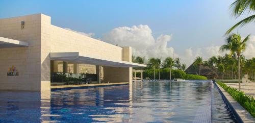 ein Haus mit einem Pool vor einem Gebäude in der Unterkunft Barceló Maya Riviera - All Inclusive Adults Only in Xpu Ha