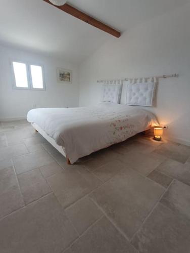 une chambre avec un grand lit dans une pièce blanche dans l'établissement Maison de charme proche Bastia, à Prunelli-di-Casacconi