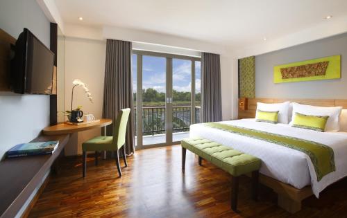 a bedroom with a bed and a desk and a balcony at d'primahotel Petitenget Seminyak 2 in Seminyak
