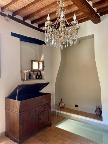 een kamer met een kroonluchter en een houten kist bij Locanda In Piazzetta - Casa in Centro Storico in San Quirico dʼOrcia