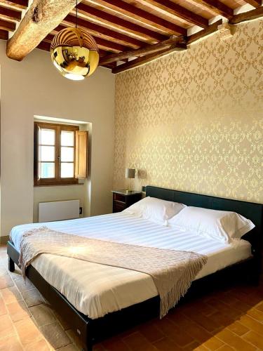 een slaapkamer met een groot bed in een kamer bij Locanda In Piazzetta - Casa in Centro Storico in San Quirico dʼOrcia