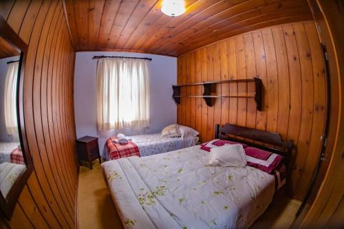 um quarto com 2 camas num quarto com paredes de madeira em Colônia SAA em Campos de Jordão